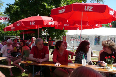 Festivalgäste unter roten UZ- und DKP-Schirmen.