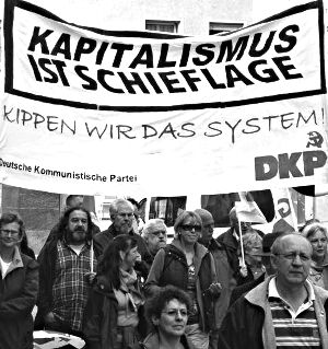 Demonstrantinnen und Demonstranten mit Transparent: »Kapitalismus ist Schieflage. Kippen wir das System. DKP«.