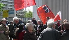 Demo vor dem griechischen Konsulat. Menschen mit roten Fahnen.