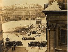 Die Reste der Vendôme-Säule, die als Symbol der Herrschaft Napoléons von den Kommunarden umgestürzt worden war; im Vordergrund Barrikaden